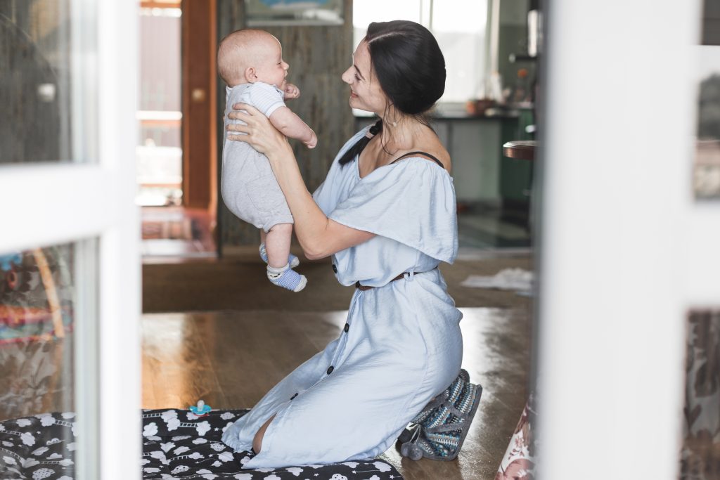 smiling-young-woman-playing-with-her-baby-home